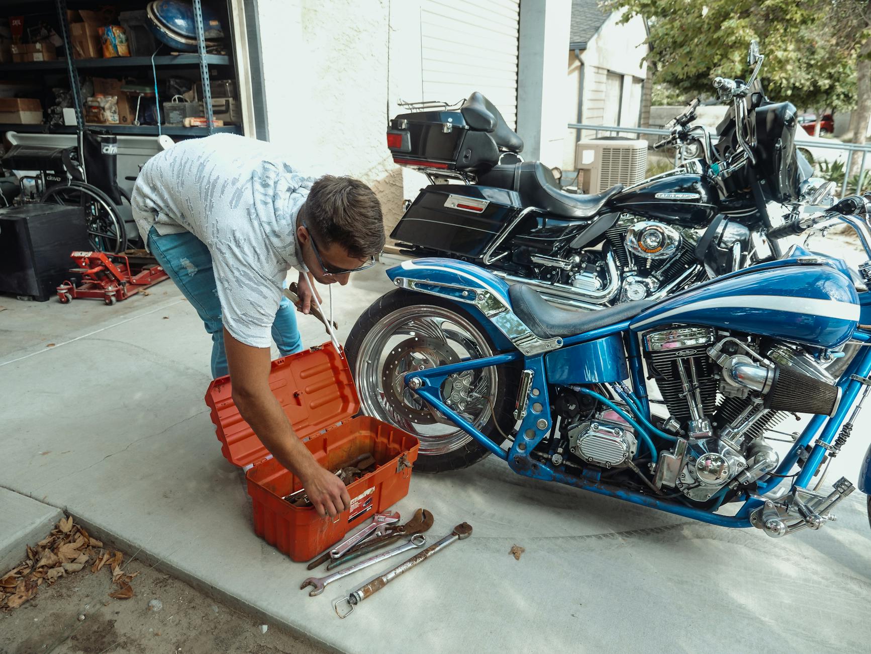 Mężczyzna serwisuje motocykl w garażu przed rozpoczęciem sezonu
